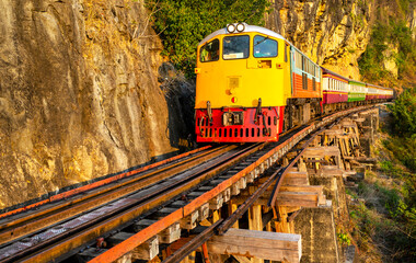 Fototapeta premium Train running across Thai-Burma Death Railway,at Tham Krasae Bridge,alongside the River Kwai,Kanchanaburi,Thailand.