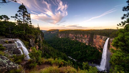 Double waterfall plunges into a green valley at sunset, scenic and vibrant