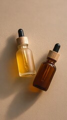 Two glass bottles with dropper caps containing amber-colored liquids, set against a neutral beige background with soft lighting.