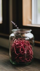 Elegant Lavender Arrangement in Glass Jar with Red Shredded Paper on Wooden Surface near Window for Home Decor and Gift Presentation