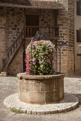 Vieux puits fleuri dans une rue du village de Beaulieu sur Dordogne (Corrèze)