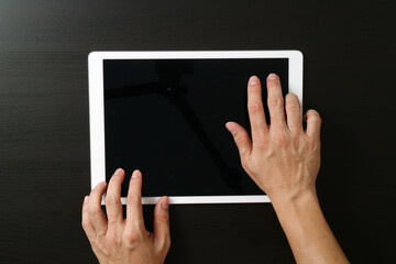 Hands holding digital tablet on black desk background
