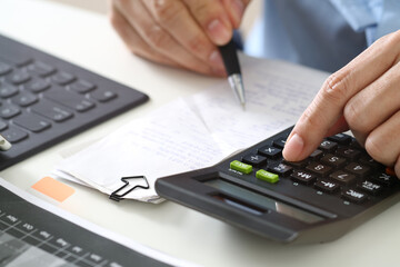 Businessman calculating expenses with calculator and financial documents