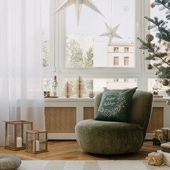 Bright window nook with green lounge chair, paper stars and white trees, gifts and a natural Christmas tree complete the serene holiday scene.