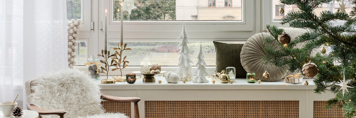 Elegant Christmas living room decor with reindeer figurine, golden candle holder, festive ornaments, and cozy sofa with green cushion.