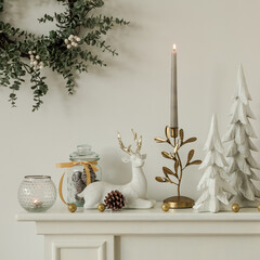 Festive mantel decorated with white reindeer figurines, gold candleholders, and seasonal greenery. A chic and minimalist holiday scene with warm and elegant details.	