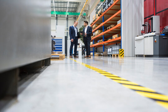 Business discussion in modern production facility with machinery