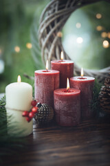 Christmas background with red and white advent candles. Natural decoration of twigs and pine cones on rustic wood with magical bokeh lights. Vertical background with space for text.