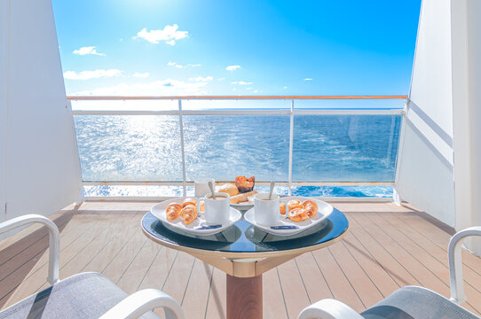 Table basse pour deux personnes avec un petit d&eacute;jeuner sur la terrasse d'une cabine balcon d'un navire de croisi&egrave;re avec vue sur la mer.