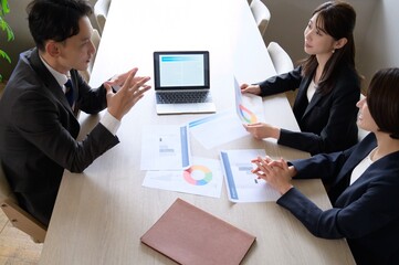 俯瞰で撮ったオフィスで会議をする日本人男女