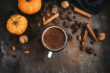 Top view of hot chocolate mug, pumpkins and spices on rustic background, cozy autumn scene