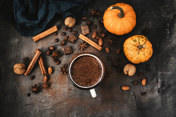 Top view of hot chocolate mug, pumpkins and spices on rustic background, cozy autumn scene