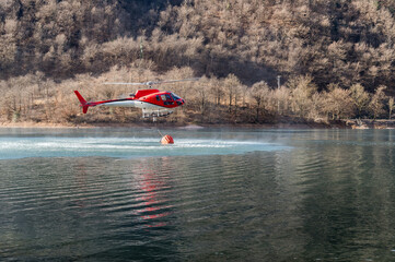 Helicopter Collecting Water from Lake Ghirla to Fight Forest Fires in Valganna, province of Varese, Lombardy, Italy