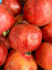 Red pomegranates piled high, textured tops visible for a rich fruit background with natural detail.