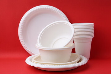 Set of disposable plastic tableware on red background, closeup