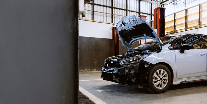 Car with open hood under repair in auto workshop