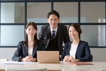 オフィスで並んでカメラ目線をする日本人男女