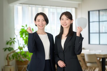 オフィスで並んでガッツポーズをする日本人女性
