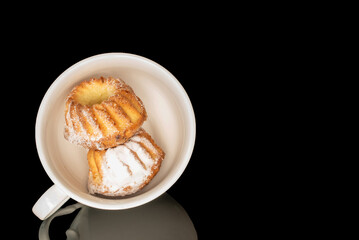 Sweet homemade cupcakes isolated on black background, close-up.