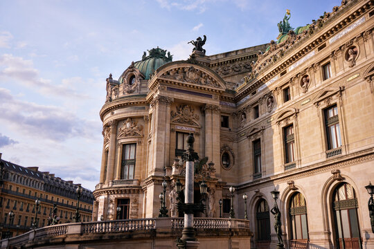 Beautiful facade of Palais Garnier Opera House in Paris, France. Historic landmark and cultural attraction with classical architecture, illuminated by evening sunlight.