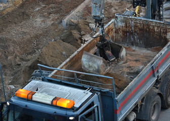 Excavator loads construction waste into the truck at construction site