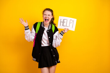 Excited young student holding help sign with vibrant yellow background emphasizing youthful energy and stylish vibe