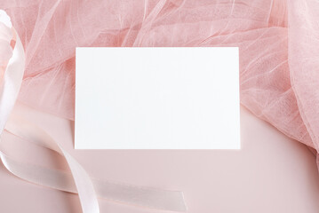 Horizontal empty card mockup template on light pastel pink fabric on pink background, design element for wedding rsvp, thank you card, greeting or invitation card. Stationery mockup
