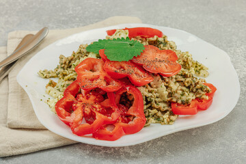 Plate of mafalda corta pasta with basil pesto, fresh tomatoes and herbs. Vegan healthy meal concept