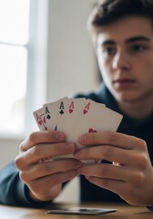 Young man holding four aces playing cards in his hands at the table