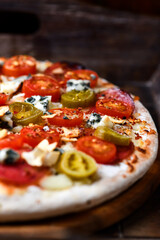 Pizza with salami, jalapeno pepper, cherry tomatoes and mozzarella cheese. Soft focus.	
