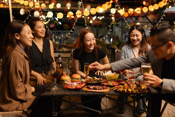 Happy Friends Celebrating Together at Night, Young Asian Group of Friends Having Fun and Toasting Drinks Outdoors At Night, Enjoying a Celebration Concept.
