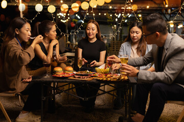 Happy Friends Celebrating Together at Night, Young Asian Group of Friends Having Fun and Toasting Drinks Outdoors At Night, Enjoying a Celebration Concept.
