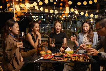 Happy Friends Celebrating Together at Night, Young Asian Group of Friends Having Fun and Toasting Drinks Outdoors At Night, Enjoying a Celebration Concept.