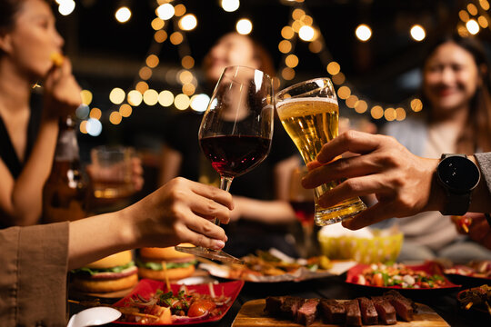 Happy Friends Celebrating Together at Night, Young Asian Group of Friends Having Fun and Toasting Drinks Outdoors At Night, Enjoying a Celebration Concept.