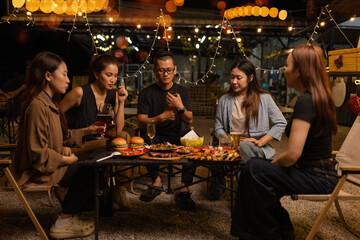 Happy Friends Celebrating Together at Night, Young Asian Group of Friends Having Fun and Toasting Drinks Outdoors At Night, Enjoying a Celebration Concept.