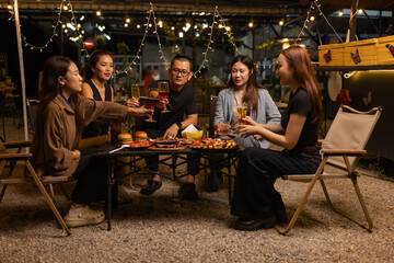 Happy Friends Celebrating Together at Night, Young Asian Group of Friends Having Fun and Toasting Drinks Outdoors At Night, Enjoying a Celebration Concept.