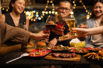Happy Friends Celebrating Together at Night, Young Asian Group of Friends Having Fun and Toasting Drinks Outdoors At Night, Enjoying a Celebration Concept.