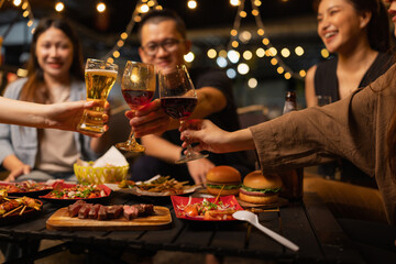 Happy Friends Celebrating Together at Night, Young Asian Group of Friends Having Fun and Toasting Drinks Outdoors At Night, Enjoying a Celebration Concept.