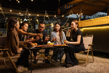 Happy Friends Celebrating Together at Night, Young Asian Group of Friends Having Fun and Toasting Drinks Outdoors At Night, Enjoying a Celebration Concept.