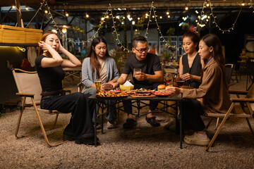 Happy Friends Celebrating Together at Night, Young Asian Group of Friends Having Fun and Toasting Drinks Outdoors At Night, Enjoying a Celebration Concept.