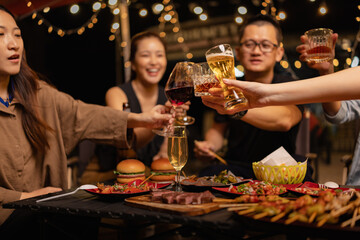 Happy Friends Celebrating Together at Night, Young Asian Group of Friends Having Fun and Toasting Drinks Outdoors At Night, Enjoying a Celebration Concept.