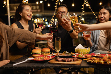 Happy Friends Celebrating Together at Night, Young Asian Group of Friends Having Fun and Toasting Drinks Outdoors At Night, Enjoying a Celebration Concept.