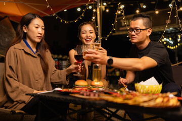 Happy Friends Celebrating Together at Night, Young Asian Group of Friends Having Fun and Toasting Drinks Outdoors At Night, Enjoying a Celebration Concept.