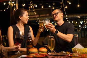 Happy Friends Celebrating Together at Night, Young Asian Group of Friends Having Fun and Toasting Drinks Outdoors At Night, Enjoying a Celebration Concept.