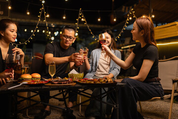 Happy Friends Celebrating Together at Night, Young Asian Group of Friends Having Fun and Toasting Drinks Outdoors At Night, Enjoying a Celebration Concept.