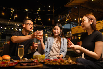 Happy Friends Celebrating Together at Night, Young Asian Group of Friends Having Fun and Toasting Drinks Outdoors At Night, Enjoying a Celebration Concept.