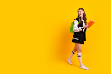 Portrait of a trendy young student holding a book and walking while enjoying the school environment...