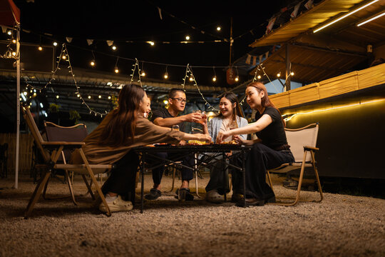 Happy Friends Celebrating Together at Night, Young Asian Group of Friends Having Fun and Toasting Drinks Outdoors At Night, Enjoying a Celebration Concept.