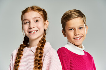 Cute preteen kids in stylish winter outfits posing happily in a studio setting