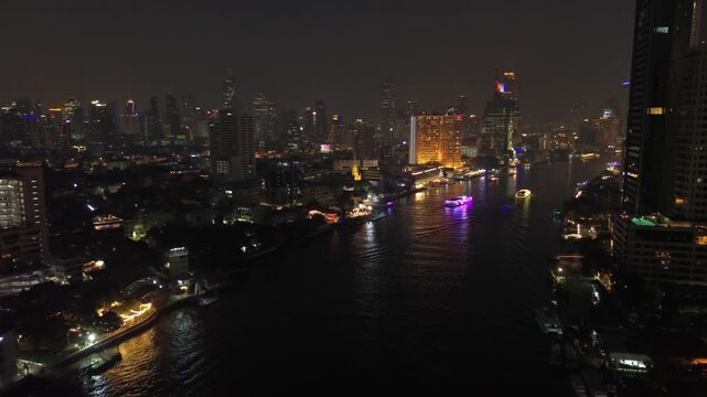 Aerial view of illuminated skyscrapers in Bangkok city and Chao Phraya River in night time, light show rays, 4k